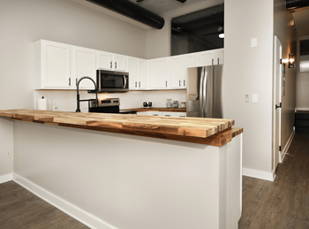 a kitchen with white cabinets and a wooden counter top